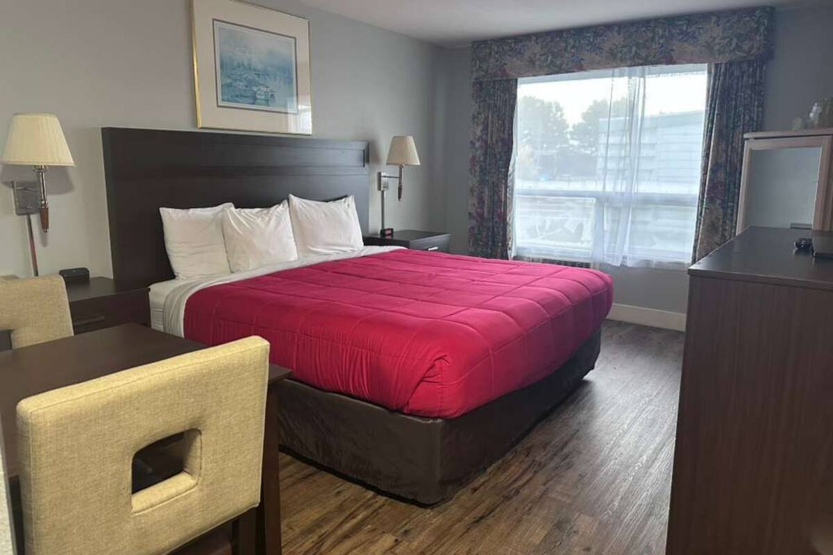 A hotel room with a large bed, two bedside tables, a desk, and a chair.