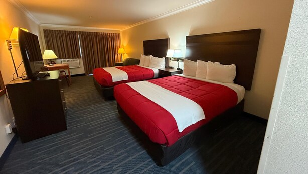 A hotel room with two beds, a desk, a chair, a lamp, and a television. - OceanShores Inn  (Ocean Shores)