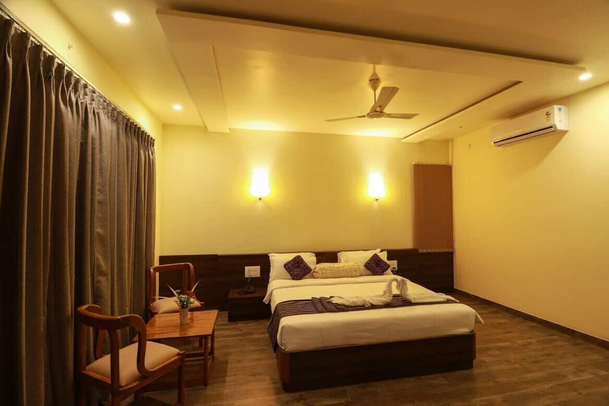 Ein Hotelzimmer mit einem Bett, einem Schreibtisch mit Stühlen, einem Deckenventilator und Wandleuchten.
