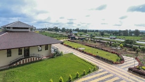 A building with a tiled roof, a paved driveway, and a well-maintained lawn. - Hotel The Cult (Hubli)