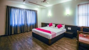 A hotel room with a large bed, wooden flooring, a desk, and a chair. - Hotel The Cult (Hubli)