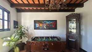 Una habitación con una mesa de fútbol de mesa, un cuadro grande, una planta en maceta y un espejo.