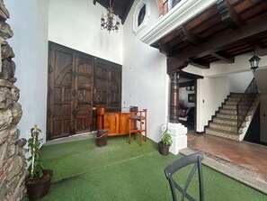 A courtyard with a wooden bench, a small table, and potted plants. There is a staircase leading to an upper level. - A lovely house in the historic center of Antigua Guatemala (Antigua Guatemala)