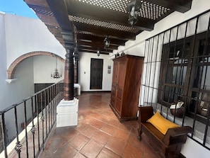 A covered outdoor area with a wooden bench, a cabinet, and a tiled floor.