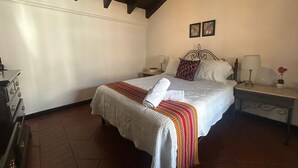 Une chambre à coucher avec un lit, des tables de chevet, une lampe et une valise.