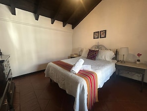 A bedroom with a bed, nightstands, a lamp, and a suitcase.