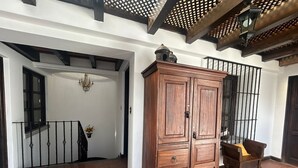 Un hall d’entrée spacieux, agrémenté d’une armoire en bois, d’un escalier et d’un lustre.