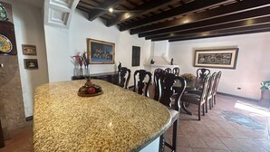 Una cocina con encimera de granito, sillas de madera y una mesa de comedor.