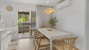 Uma cozinha moderna com armários brancos, forno embutido e janela com vista para um jardim.