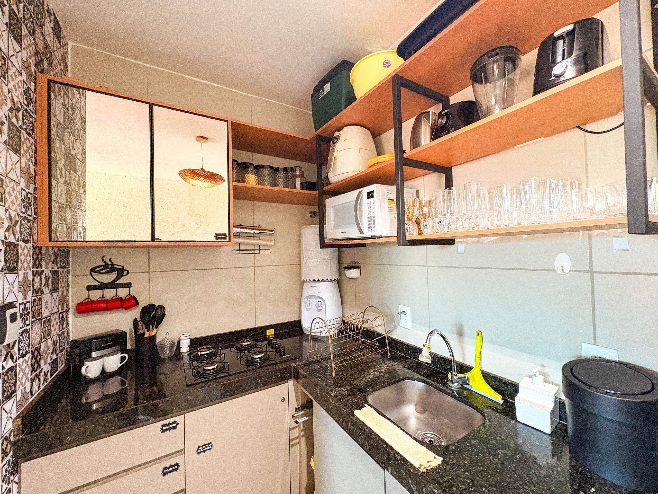 A kitchen with a microwave, coffee maker, and a sink.