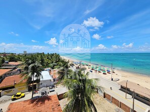 Uma área costeira com praia, palmeiras e céu claro.