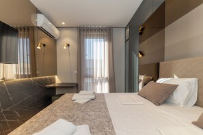 Et moderne hotelværelse med en stor seng, et siddeområde med sofa, et lille bord og et spejl.