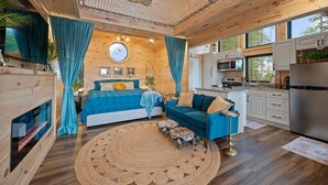 Ein gemütliches Blockhauszimmer mit Bett, blauem Sofa und Küchenbereich.