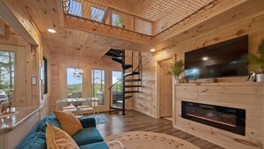 Ein geräumiger Wohnbereich mit großem Fernseher, Kamin und gemütlicher Sitzecke.