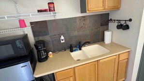 Una cocina compacta equipada con refrigerador, cafetera y lavamanos.