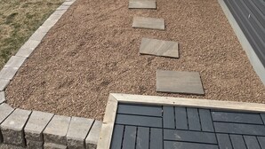 Una construcció de fusta amb porta i finestres, situada sobre grava i amb pedres perenques que hi condueixen, al costat d'una casa.