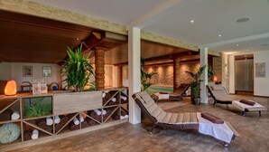 Un espacio de spa con estantes de madera, sillones de descanso y una pared de piedra.