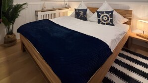 A bedroom with a wooden bed, a ceiling fan, a window with blinds, a bedside table with a lamp, and a potted plant. - Apartment in 'Haus Anni' with Terrace and Wi-Fi (Bad Zwischenahn)