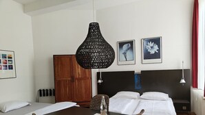 Una camera d'hotel con un letto, una scrivania, una sedia, un armadio in legno e due quadri appesi al muro.