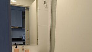 Une salle de bain moderne avec un lavabo blanc, des meubles en bois foncé et une cabine de douche en verre.
