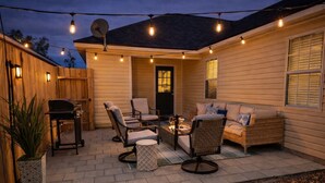 Eine Terrasse mit Gartenmöbeln, einem Grill und Lichterketten.