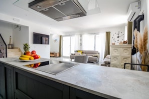 A modern kitchen with a central island, a dining area with a sofa and chairs, and a living room with a TV.