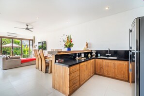 Eine moderne Küche mit Holzausstattung, einer schwarzen Arbeitsplatte und einem eingebauten Kühlschrank.