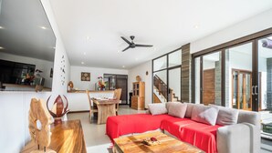 Un salon moderne comprenant un canapé, une table basse et un coin repas avec une table et des chaises en bois.