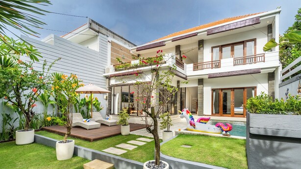 Une maison moderne à deux étages dotée d’une piscine, d’un espace salon extérieur et de plantes en pot.