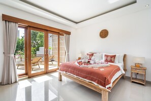 A bedroom with a large bed, a wooden nightstand, a sliding glass door leading to an outdoor area, and a ceiling light fixture. - Villa Avaluna (by JB Villas) (Legian)
