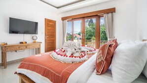 Une chambre à coucher avec un lit, une télévision, un bureau en bois et une fenêtre avec des rideaux.