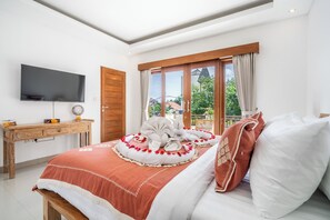 A bedroom with a bed, a TV, a wooden desk, and a window with curtains. - Villa Avaluna (by JB Villas) (Legian)