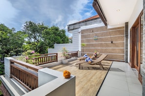 Eine moderne Terrasse im Freien mit Holzboden, Lounge-Sesseln und Kübelpflanzen.