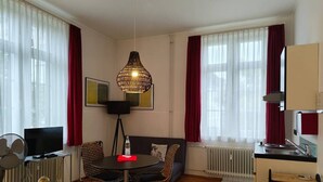 A modern living room with a sofa, a dining table, a TV, and a kitchen area. - Superior Studio for 3 in Konstanz (Konstanz)