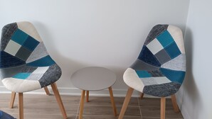 Dos sillones con un estampado geométrico, una mesita redonda y baldosas de madera.