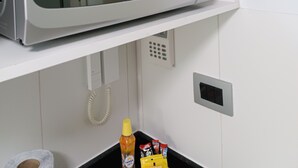 Un horno microondas sobre un estante blanco en una cocina.