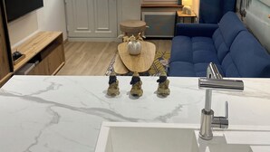 Un salon moderne avec un lavabo en marbre, un canapé bleu, un téléviseur et un élément décoratif mural.