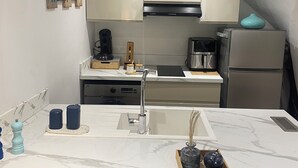 Une cuisine moderne dotée d’un plan de travail en marbre, d’appareils électroménagers en acier inoxydable et d’un four encastré.