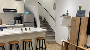 Une cuisine moderne dotée d’un îlot central, de tabourets de bar, d’une table à manger agrémentée d’un vase et d’un escalier menant à un niveau supérieur.