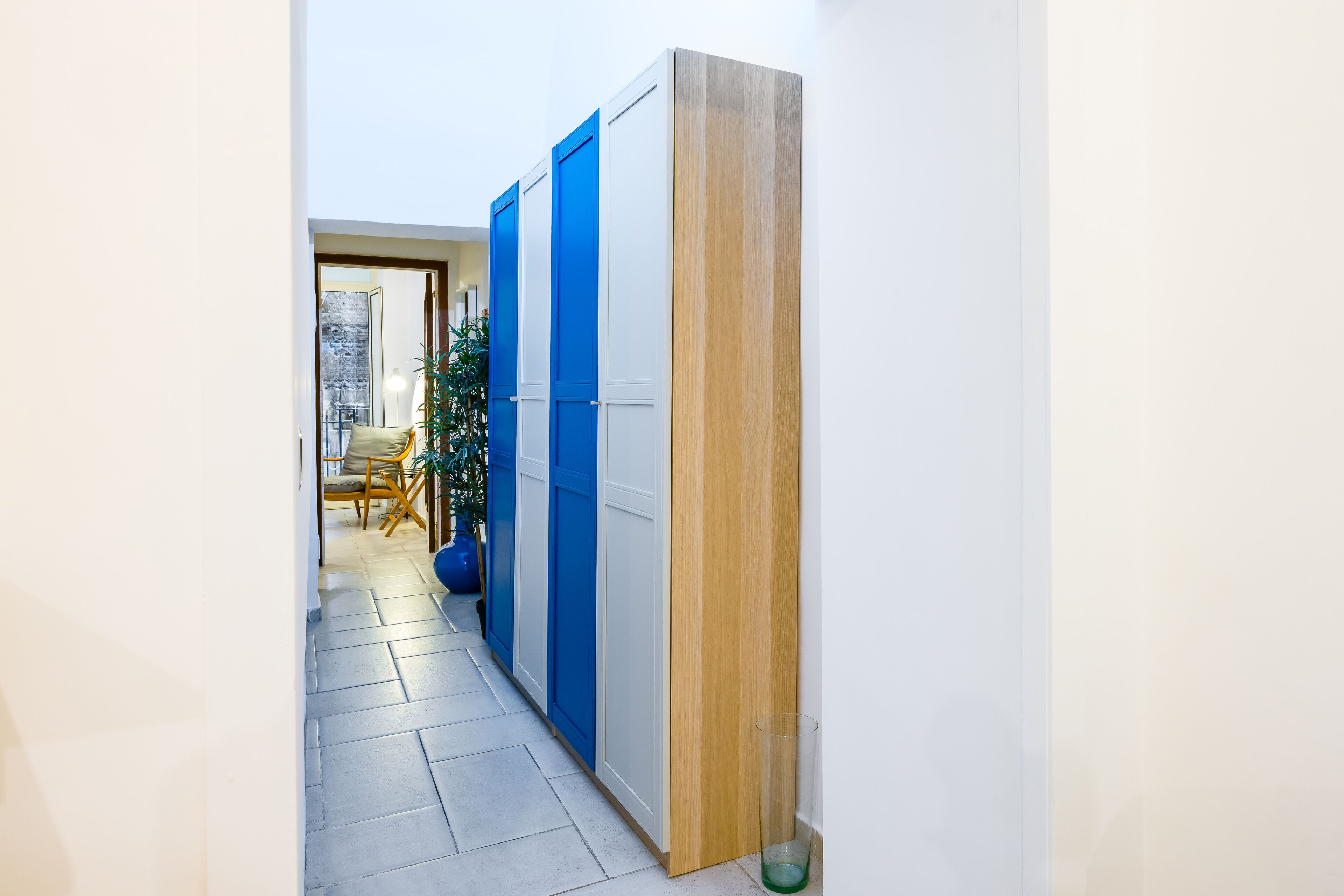 A hallway with a blue and white wardrobe, a wooden door, and a tiled floor.
