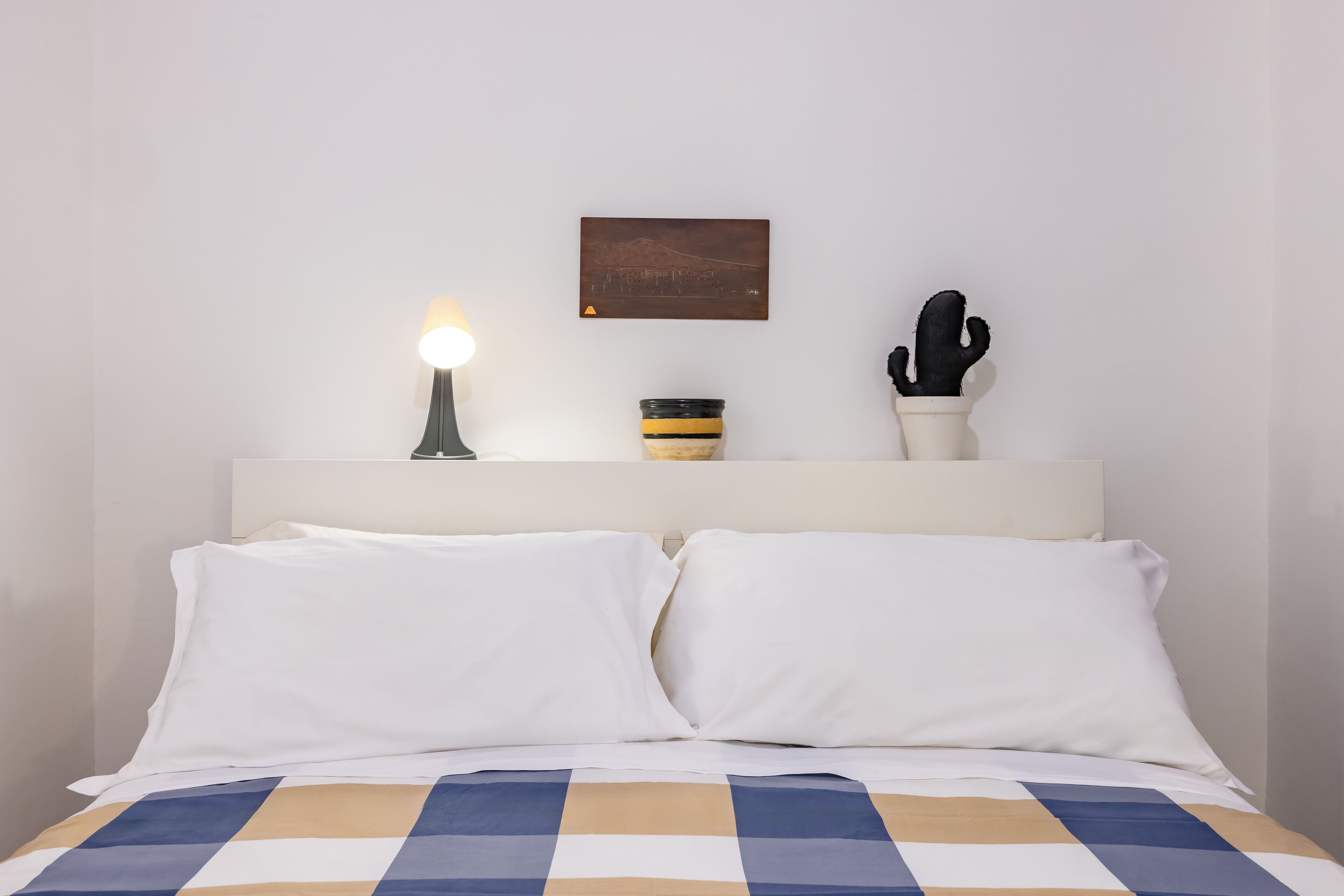 A neatly made bed with white pillows and a checkered bedspread.