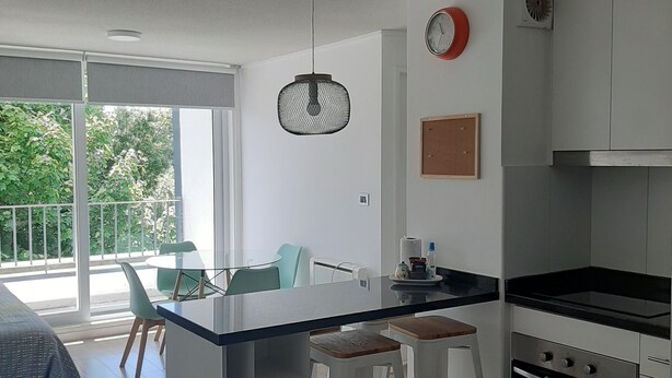A modern kitchen with a central island, white cabinetry, and a dining area with a table and chairs. - Kasa and family 220 (Valdivia)