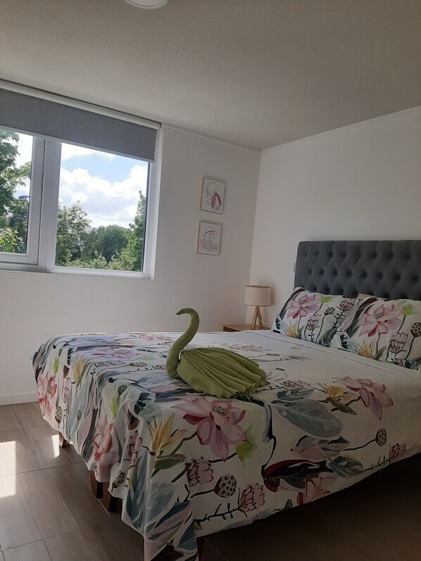 A bedroom with a bed, a window, and a nightstand with a lamp.