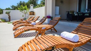Une terrasse sur le toit, dotée de chaises longues en bois, d’un espace repas et offrant une vue sur le paysage environnant.