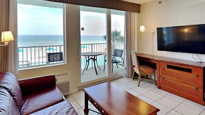 Ein Hotelzimmer mit Balkon, Fernseher, Sofa und Esstisch.