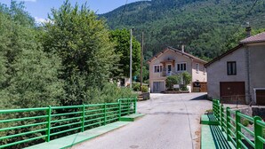 Une route menant à un bâtiment, avec une clôture métallique verte d’un côté.