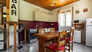 Une cuisine compacte avec une table et des chaises en bois, une cuisinière, un four à micro-ondes et un réfrigérateur.