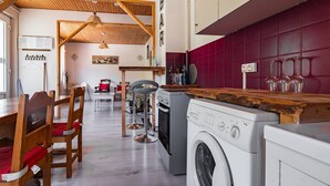Un espace buanderie avec des machines à laver, un coin bar et un espace repas avec des chaises et une table en bois.
