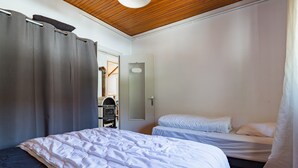 Une chambre avec deux lits, un plafond en bois et une porte donnant sur une salle de bain.