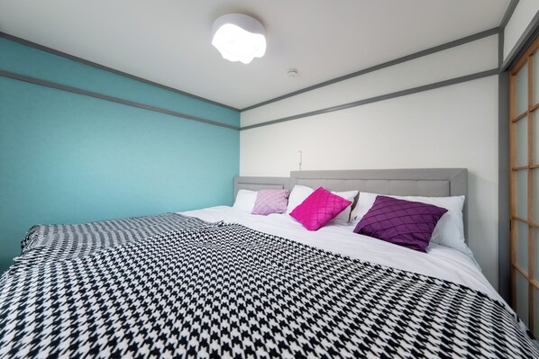 Ein Schlafzimmer mit einem bettbezug mit Hounds-Tooth-Muster, einem grauen Kopfteil und einer türkisfarbenen Akzentwand.